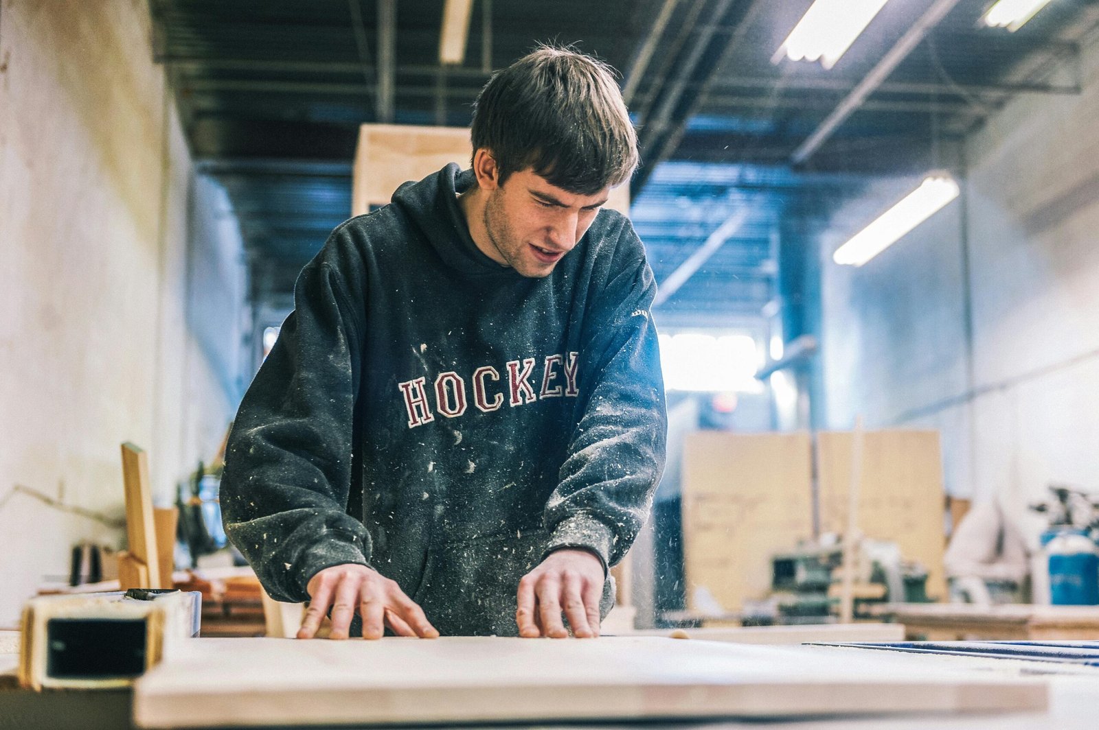 A committed carpenter sanding wood in a bustling workshop, showcasing precision and skill.